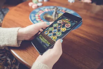 A man focused on his laptop with live stats in the background, highlighting the dedicated sports and gaming features of the K677 mobile app.